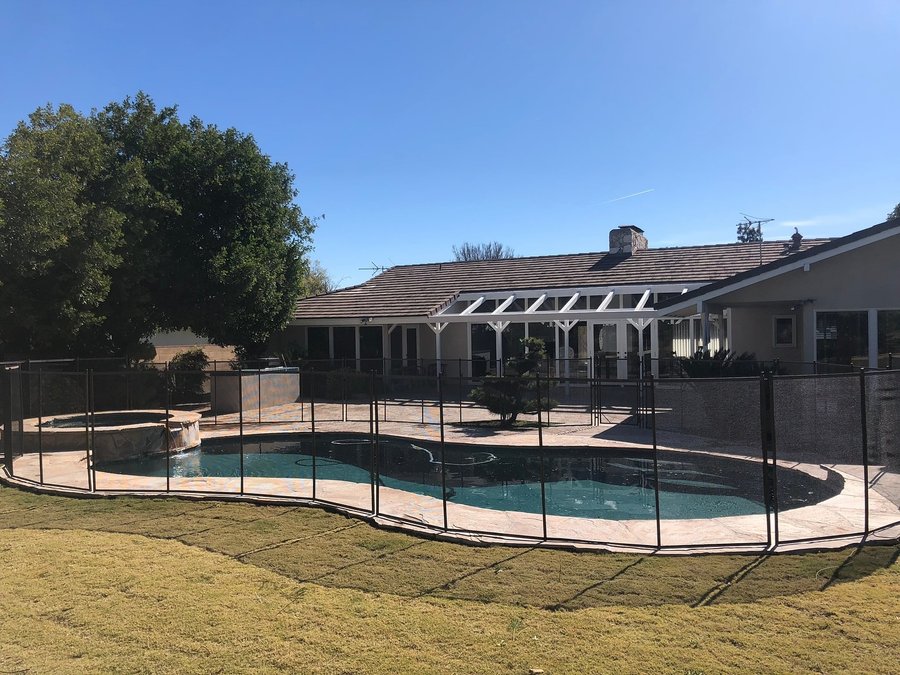 mesh pool safety fence installed around a backyard pool